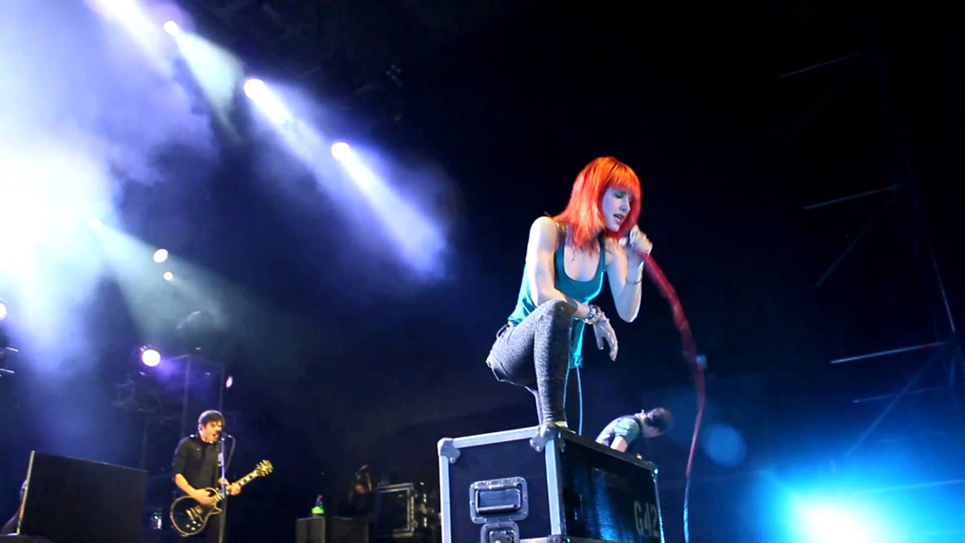 Hayley Williams of Paramore playing live at a concert.